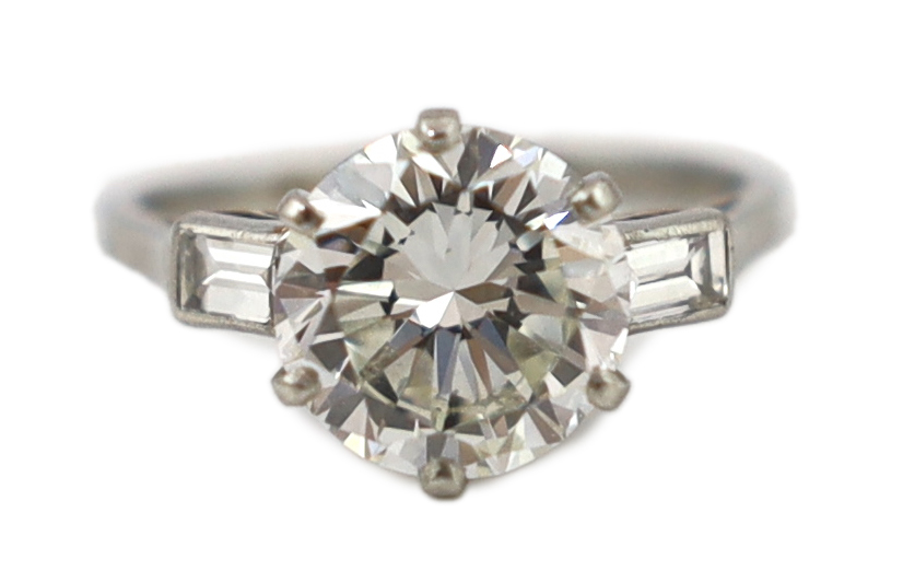 A good platinum or white gold set single stone diamond ring, with two stone baguette cut diamond set shoulders